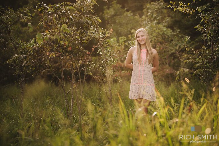 Casey standing near some tree in a field during her senior portrait session near Chattanooga, Tennessee