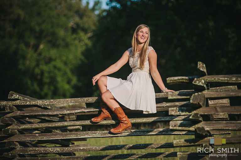 Casey sitting on a fence smiling off camera during her senior session near Chattanooga, Tennessee