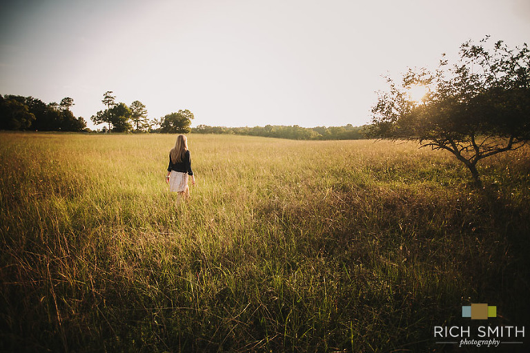 Casey with her back to the camera in a large field during her senior session at the Chickamauga Battlefields