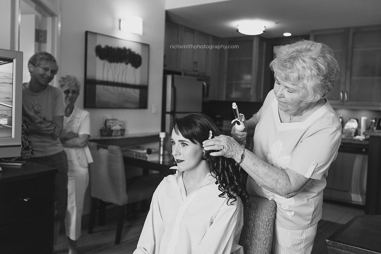 Grandmother does brides hair as mom and grandmother look on.