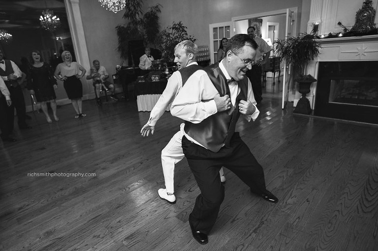 Groom and the brides dad dances together on dance floor.
