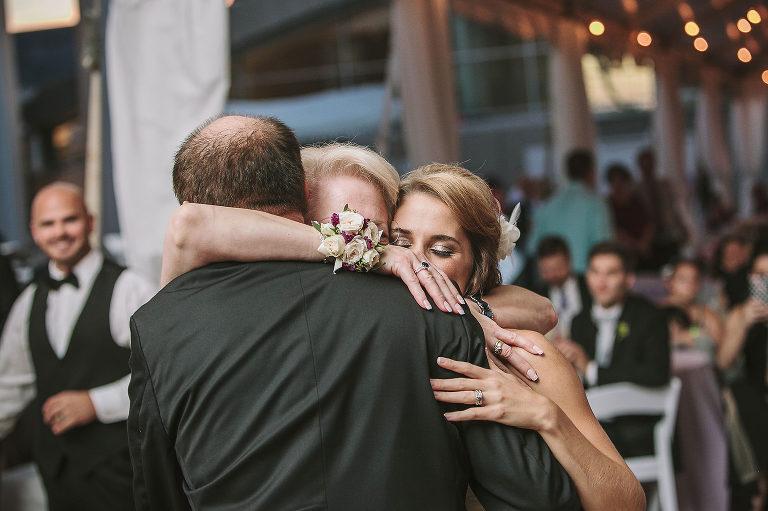 bride hugging her mom and dad at the wedding reception 