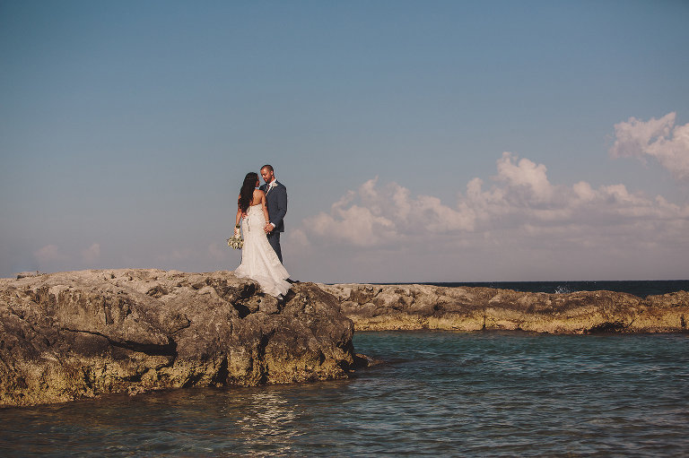 bride and groom on the rocks at the beach in Mexico
