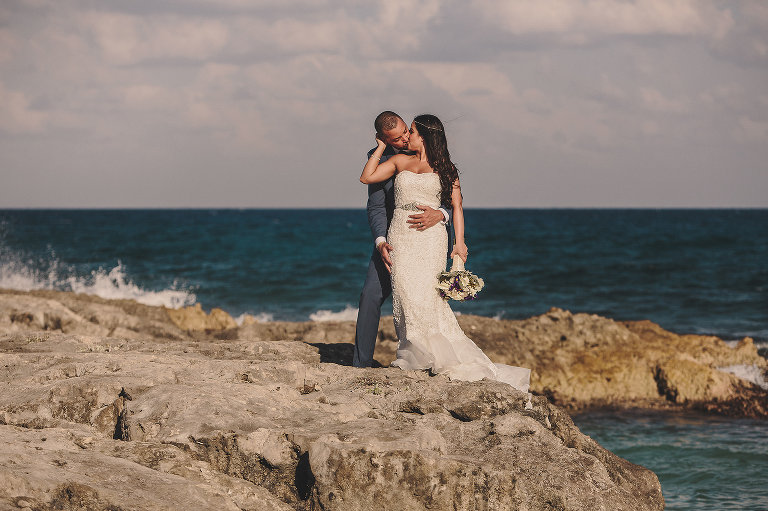 bride and groom kissing on the rocks on the beach in Mexico 