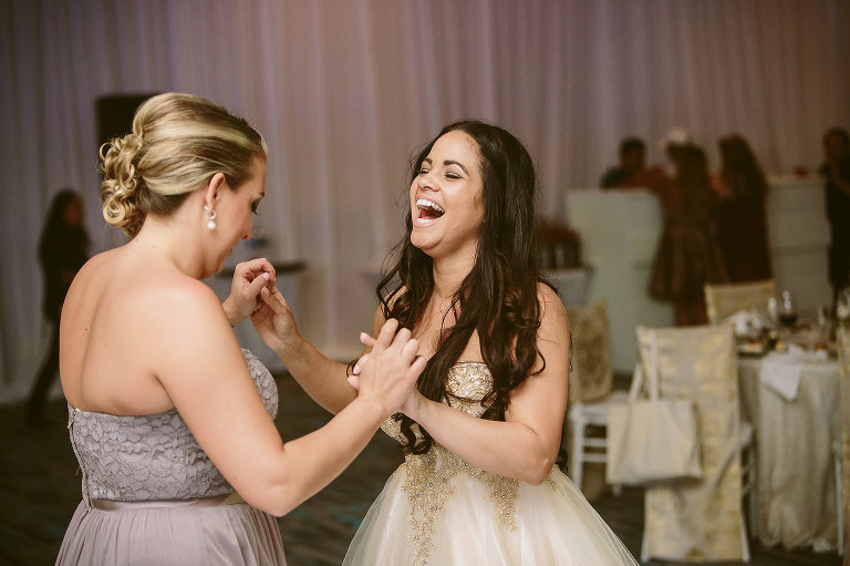 bride and bridesmaid laughing and dancing 