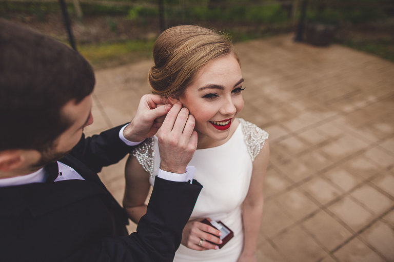 groom putting earrings on bride