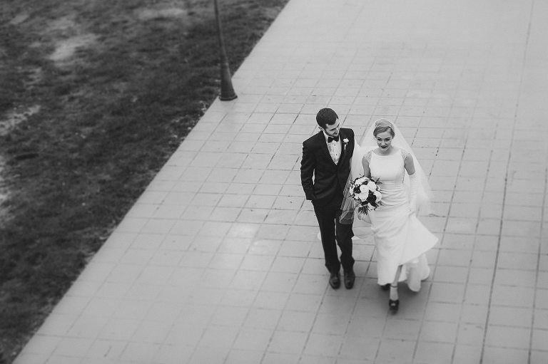 artistic black and white image of bride and groom walking 