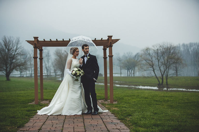 bride and groom outdoors with umbrella on rainy day 
