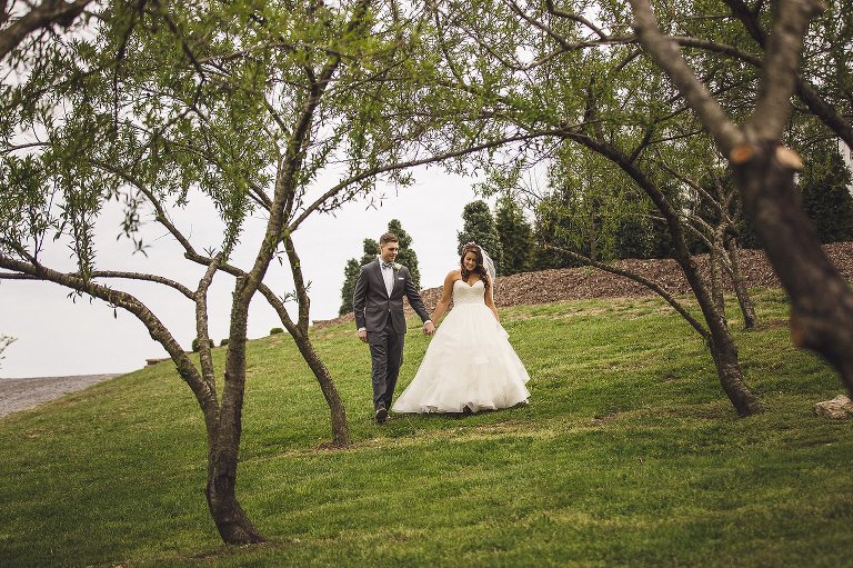 bride and groom walking through an orchard