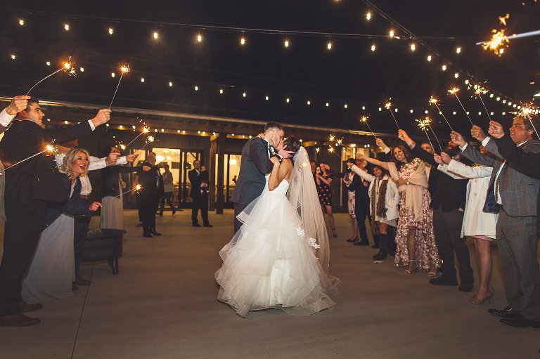 bride and groom kiss during their wedding exit with sparklers