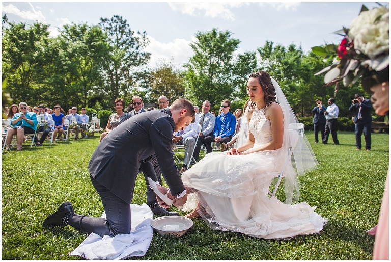 groom washing brides feet during ceremony 