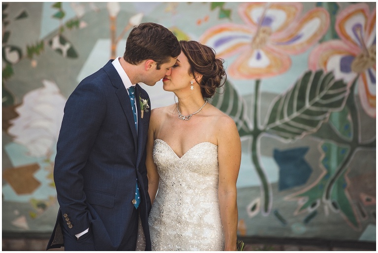 bride and groom kiss after ceremony in front of mural