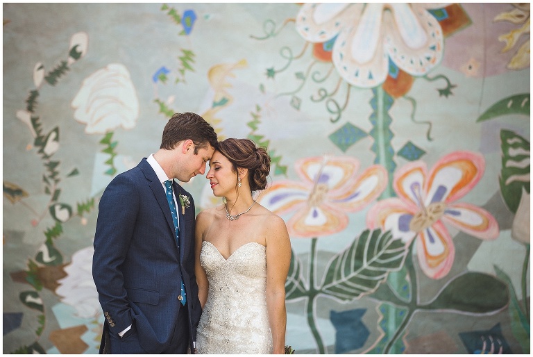 bride and groom share a sweet moment after ceremony in front of mural 