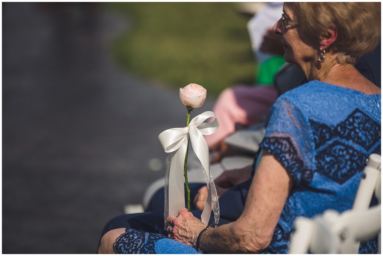 grandparent holding rose during wedding ceremony 