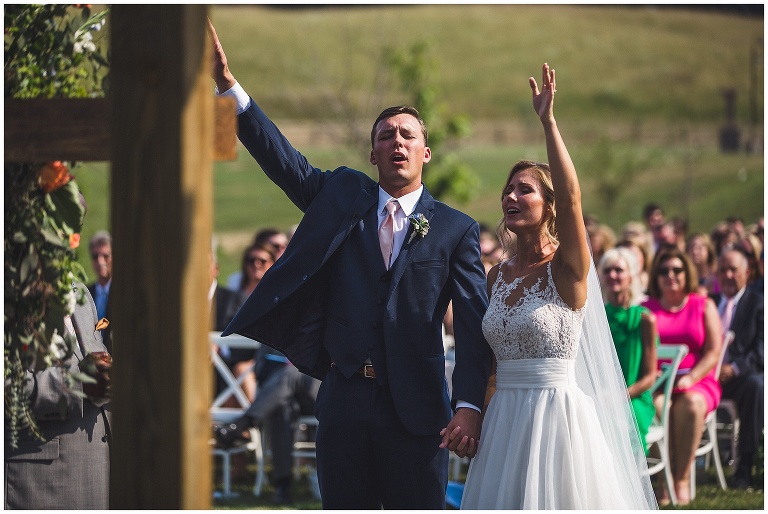 bride and groom with lifted hands during ceremony 