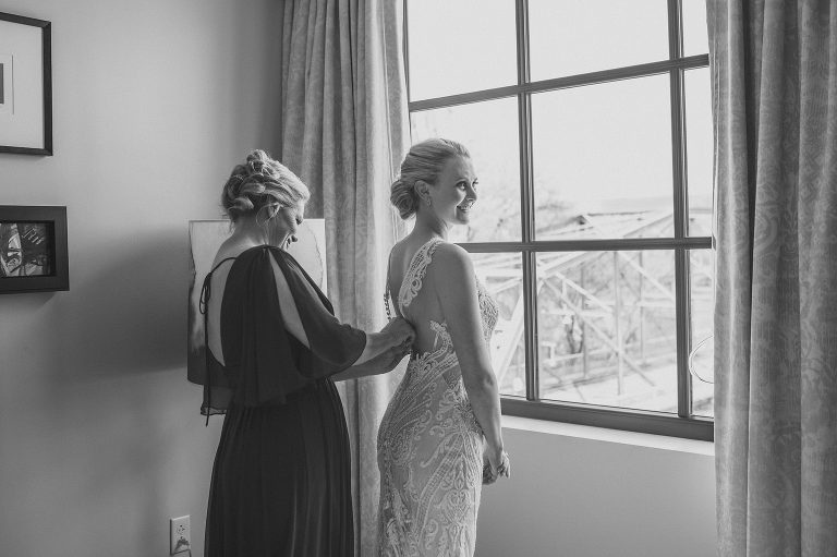 bride getting wedding dress buttoned by her mom