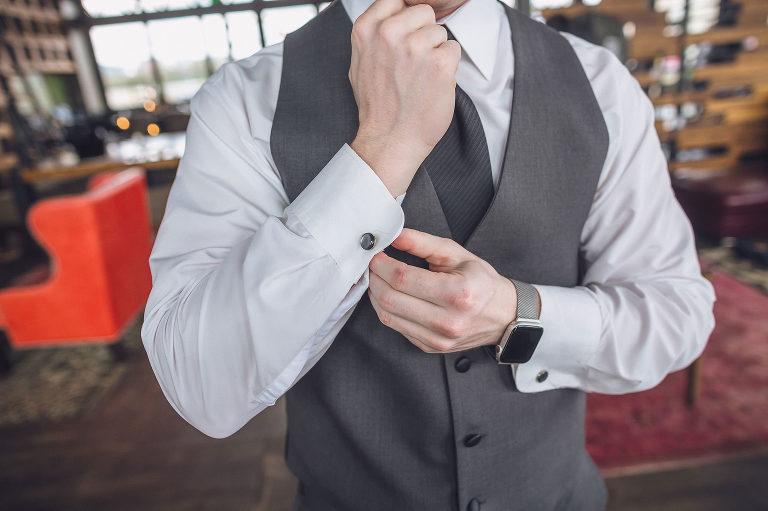 groom getting ready and buttoning shirt