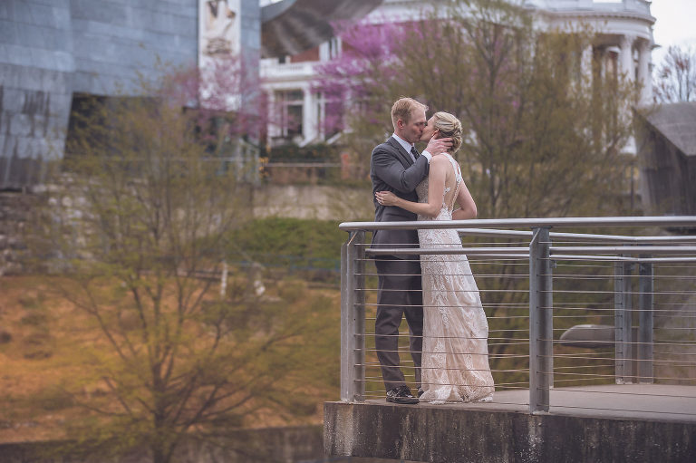 bride and groom kissing on glass bridge