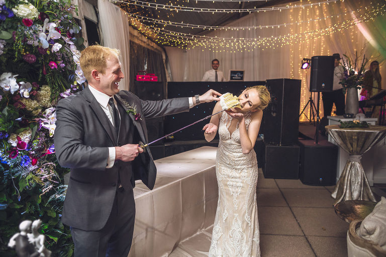 groom feeding bride wedding cake with sword